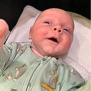 Koa is registered to the contest to win money with this photo: baby, infant, smiling, onesie, bunny_prints, blanket, soft, cute, hand, face, head, skin, lying_down, clothing, gold_pin, indoors, child, person, newborn, portrait