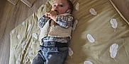 Louis a rejoint le concours — aidez-le/la à gagner de superbes lots ! baby, chair, child, clothing, curious, feather_pattern, floor, furniture, indoor, infant, lying_down, mattress, pants, person, plaid_shirt, socks, table, toy, vest, wooden_floor