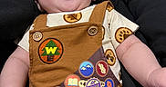 Grayson joined the competition — help win amazing prizes! baby, child, smiling, laughing, infant, overalls, badge, brown_clothing, patterned_shirt, cushion, black_background, happy, cute, portrait, indoor, young_child, person, skin, face, expression