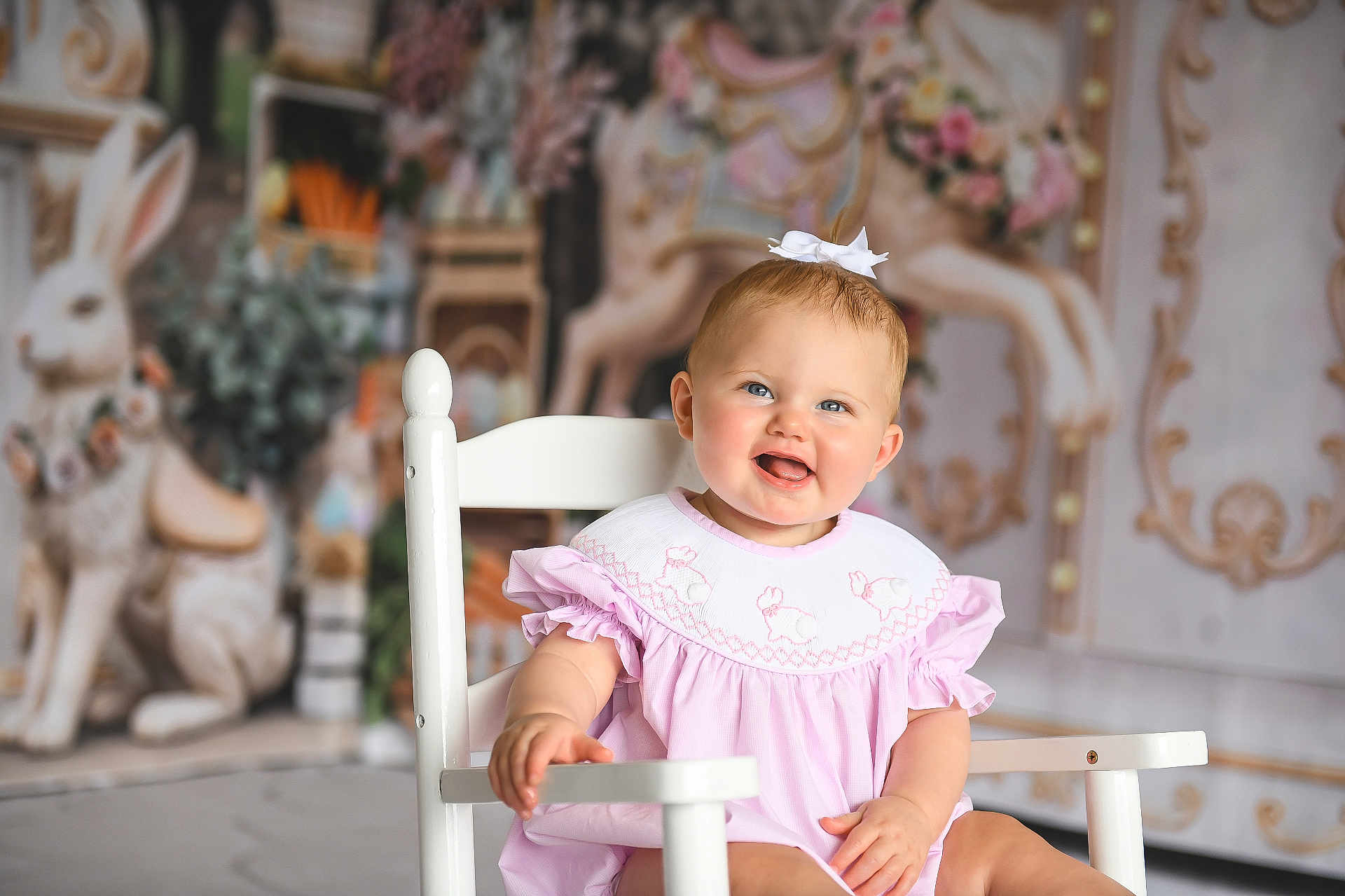 Berkley joined the competition — help win amazing prizes! baby, child, toddler, smiling, white_chair, pink_dress, bow, blue_eyes, portrait, sitting, indoor, studio, decorative_background, carousel, rabbit_figure, floral, hands, cute, happy, soft_lighting