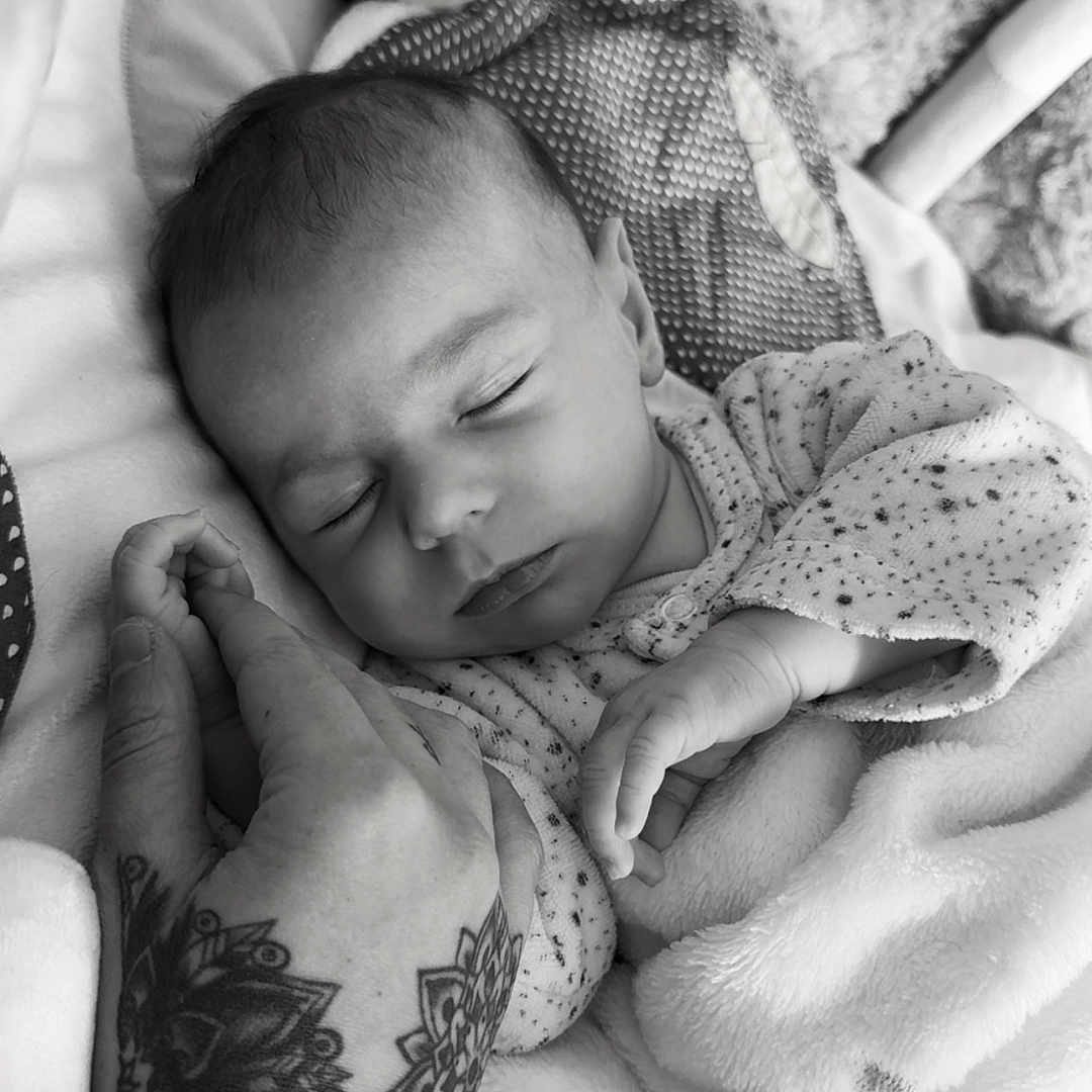 Marcellynnio participe au concours pour gagner de l'argent avec cette photo : baby, black_and_white, blanket, close_up, clothing, comfort, cozy, cute, fingers, hand, indoor, infant, peaceful, person, portrait, resting, skin, sleeping, soft_texture, tattoo