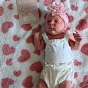 Willow is registered to the contest to win money with this photo: baby, infant, newborn, pink, flower_headband, white_clothing, polka_dots, blanket, heart_pattern, milestone_card, cute, lying_down, soft_texture, sleepy_cat_illustration, portrait, child, face, skin, headwear, baby_girl