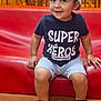 Timothe participe au concours pour gagner de l'argent avec cette photo : toddler, child, smiling, sitting, bucket_hat, shorts, sandals, red_bench, indoor, happy, cute, face, person, footwear, clothing, casual, short_sleeve, dinosaur_pattern, young_child, portrait