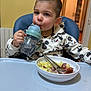 Timothe participe au concours pour gagner de l'argent avec cette photo : toddler, child, mickey_mouse, hoodie, high_chair, sippy_cup, food, bowl, fork, spoon, indoor, kitchen, furniture, table, drink, face, person, clothing, young_child, eating