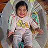 baby, child, infant, smiling, happy, portrait, bouncer, baby_seat, indoor, home, pajamas, pink_clothing, cartoon, bird_graphic, dark_hair, sitting, lying_down, playful, patterned_blanket, household_background