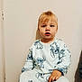 toddler, child, pajamas, blonde_hair, sitting, indoor, wall, clothing, person, cute, young_child, portrait, casual, relaxed, small_child, face, human, light_skin, looking_away, seated