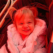 Eva a rejoint le concours — aidez-le/la à gagner de superbes lots ! toddler, child, smile, happy, coat, fluffy, stroller, baby, face, hair, jacket, warm_clothing, indoor, seat, person, cute, young_child, portrait, baby_face, cozy