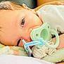 Fabian is registered to the contest to win money with this photo: baby, pacifier, blanket, infant, close_up, soft_texture, white_clothing, lying_down, cute, child, newborn, face, skin, hair, resting, comfort, indoor, peaceful, small_hand, light