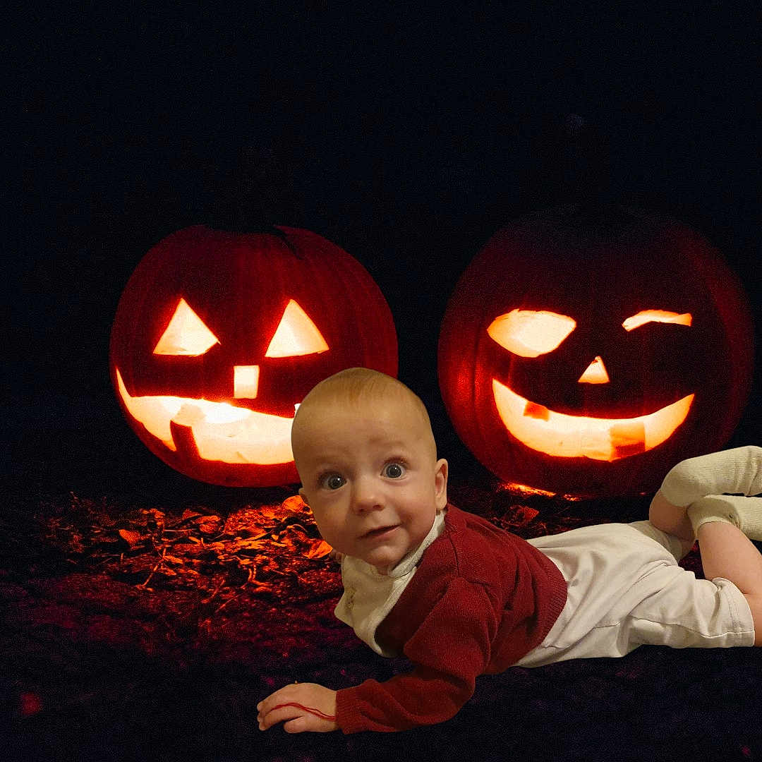 Kaloyan joined the competition — help win amazing prizes! baby, infant, jack_o_lantern, pumpkin, halloween, glow, night, darkness, costume, outdoor, face, smile, cute, child, orange, light, holiday, festive, lying_down, curious