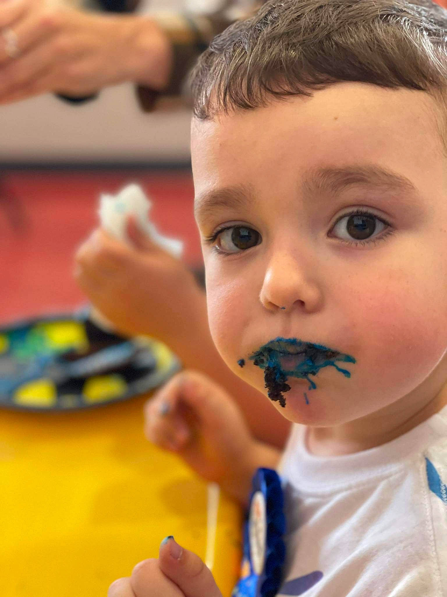 Corbin is registered to the contest to win money with this photo: child, comfort_food, eating, eyelash, face, finger, fun, gesture, hand, happy, leisure, nail, nose, person, play, recreation, sweetness, table, thumb, toddler