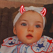 Ashlyn Rae joined the competition — help win amazing prizes! baby, bib, blue_eyes, child, close_up, couch, cute, doodle, expression, face, headband, headwear, indoors, infant, patterned_clothing, portrait, red_horns, seated, soft_lighting, young_child