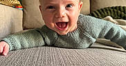 Pablo a rejoint le concours — aidez-le/la à gagner de superbes lots ! baby, smiling, child, indoor, couch, knitted_sweater, happy, face, person, home, green_wall, cushion, portrait, cozy, infant, cute, lying_down, texture, head, expression