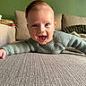 baby, smiling, child, indoor, couch, knitted_sweater, happy, face, person, home, green_wall, cushion, portrait, cozy, infant, cute, lying_down, texture, head, expression