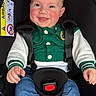 baby, child, car_seat, smiling, happy, denim, jacket, green_clothing, white_sleeves, safety_harness, pacifier, infant, cute, rosy_cheeks, indoor, portrait, seated, clothing, closeup, person