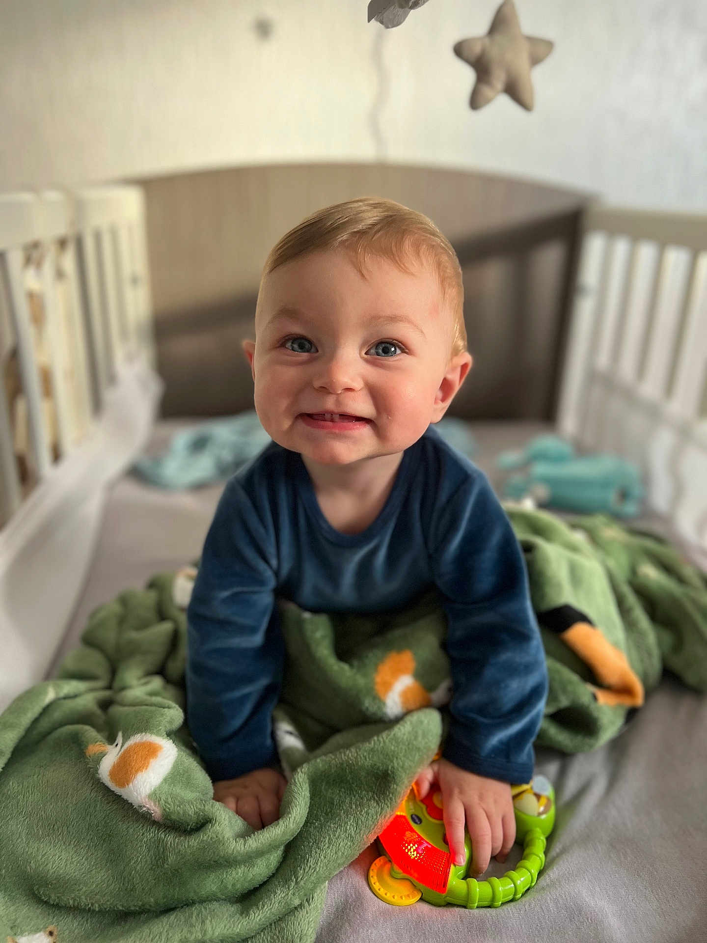 Aaron participe au concours pour gagner de l'argent avec cette photo : baby, child, crib, blanket, toy, smile, blue_eyes, indoor, plush, star, soft, happy, cute, infant, clothing, hand, face, light, green, cozy