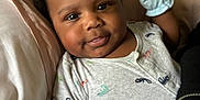 Mason is registered to the contest to win money with this photo: baby, infant, child, onesie, mittens, bed, pillow, blanket, pacifier, cute, smiling, lying_down, indoors, sleepwear, skin, hair, face, tongue_out, closeup, happy
