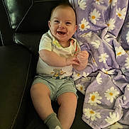 Jasper joined the competition — help win amazing prizes! baby, smiling, happy, sitting, couch, blanket, purple_blanket, daisy_pattern, clothing, shorts, socks, indoor, child, face, hands, feet, leather_couch, cozy, cute, portrait