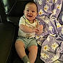 baby, smiling, happy, sitting, couch, blanket, purple_blanket, daisy_pattern, clothing, shorts, socks, indoor, child, face, hands, feet, leather_couch, cozy, cute, portrait