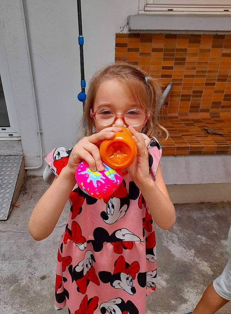 Djoulya participe au concours pour gagner de l'argent avec cette photo : arm, baby_toddler_clothing, child, dress, drinking, eating, finger, fun, hand, happy, nose, orange, pattern, person, pink, play, standing, t_shirt, tableware, toddler