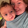 Donovan is registered to the contest to win money with this photo: baby, woman, smile, face, indoor, portrait, piercing, hand, fabric, holding, kitchen, light, person, skin, nail_polish, ring, curly_hair, redhead, child, closeup