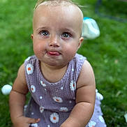 Payton joined the competition — help win amazing prizes! baby, child, outdoor, grass, purple_dress, flower_pattern, cup, pink, toddler, cute, face, tongue, hand, summer, play, nature, skin, person, expression, sitting