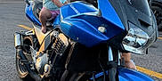 Payton is registered to the contest to win money with this photo: child, toddler, motorcycle, blue_motorcycle, kawasaki, parking_lot, sunset, smiling, outdoor, vehicle, person, asphalt, helmet_absent, casual_clothing, happy, two_wheeler, transportation, road, parked_vehicle, nature