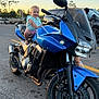 child, toddler, motorcycle, blue_motorcycle, kawasaki, parking_lot, sunset, smiling, outdoor, vehicle, person, asphalt, helmet_absent, casual_clothing, happy, two_wheeler, transportation, road, parked_vehicle, nature
