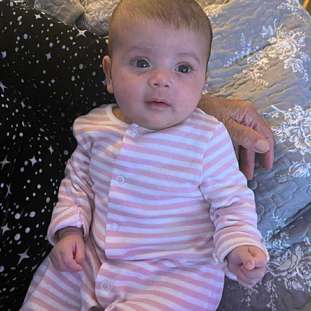 Metiem joined the competition — help win amazing prizes! adult_hand, baby, bedroom, clothing, cute, fabric, face, hand, indoor, infant, newborn, pattern, person, pink_stripes, portrait, quilt, sitting, sleepwear, soft_lighting, young_child