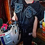 William is registered to the contest to win money with this photo: child, boy, helmet, sports_gear, black_jersey, batman_cap, barefoot, indoor, wooden_floor, furniture, television, books, cabinet, toy, casual, smile, portrait, home, person, floor
