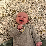 Romy a rejoint le concours — aidez-le/la à gagner de superbes lots ! baby, smiling, joyful, pacifier, onesie, cozy, blanket, floral_pattern, infant, happy, lying_down, cute, child, face, hands, indoor, portrait, soft_texture, relaxed, playful