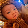 baby, infant, hoodie, fur_clothing, cute, face, portrait, child, warm_clothing, indoor, person, soft_texture, expression, eyes, closeup, young_child, adorable, cuddly, warmth, cozy