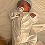Terry is registered to the contest to win money with this photo: baby, newborn, pacifier, hat, onesie, sleeping, infant, blanket, white_clothing, soft, cute, peaceful, resting, child, bed, cozy, hands, face, young, indoor