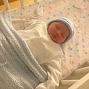Terry is registered to the contest to win money with this photo: baby, newborn, sleeping, crib, blanket, hat, white_clothing, bedding, pastel_colors, wooden_crib, infant, peaceful, indoors, cute, child, baby_girl, baby_boy, soft_texture, nursery, pacifier
