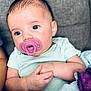 Olivia is registered to the contest to win money with this photo: baby, infant, pacifier, onesie, hands, face, eyes, skin, couch, blanket, purple, mint_green, closeup, portrait, cute, resting, indoor, child, young, snuggled