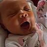baby, sleeping, yawning, infant, onesie, floral_pattern, closeup, face, mouth_open, pink, soft_lighting, newborn, cute, cozy, portrait, child, skin, peaceful, resting, indoor