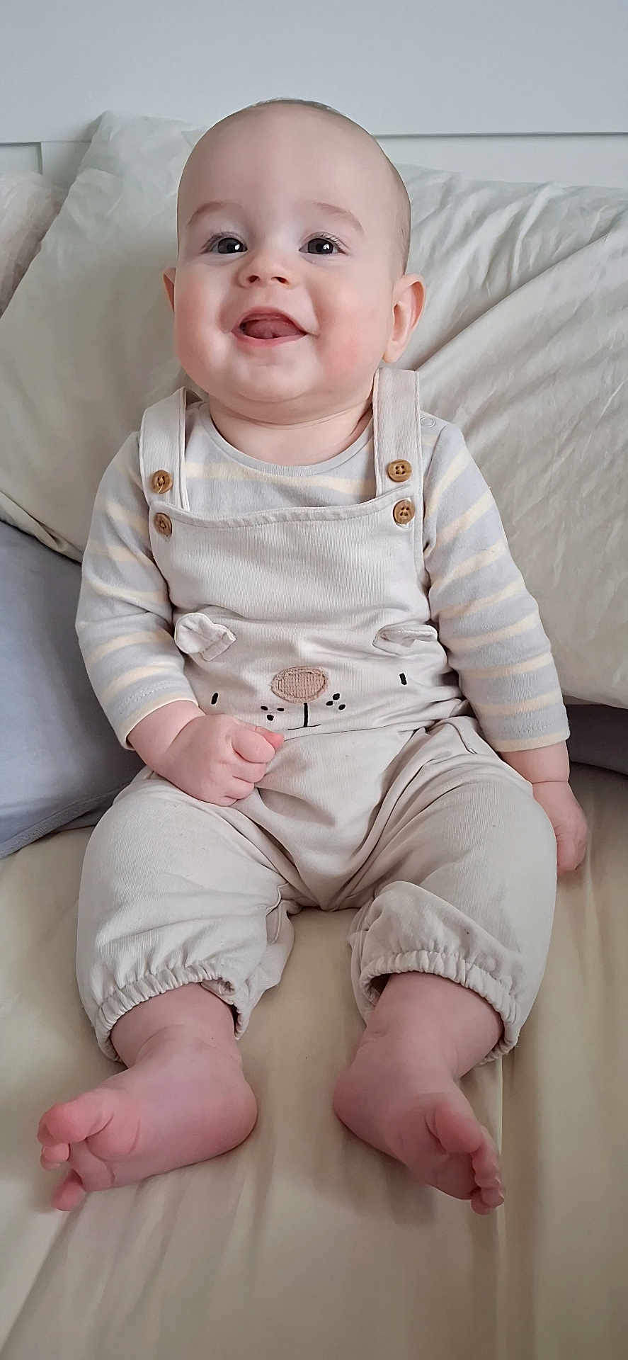 Rory joined the competition — help win amazing prizes! baby, child, smiling, sitting, bed, pillow, blanket, overalls, clothing, cute, happy, infant, tongue, face, head, skin, foot, hand, indoors, person
