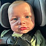 baby, child, car_seat, harness, blue_eyes, green_shirt, infant, close_up, face, seatbelt, safety, portrait, skin, headrest, sunlight, expression, person, young_child, seat, indoor