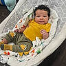 Elijah joined the competition — help win amazing prizes! baby, infant, child, curly_hair, yellow_shirt, dinosaur_pants, baby_rocker, blanket, indoor, floor, cute, smile, clothing, person, relaxing, comfort, sitting, portrait, young_child, home