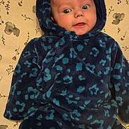 Louana participe au concours pour gagner de l'argent avec cette photo : baby, blanket, blue_clothing, child, cozy, curious, cute, face, floral_pattern, hooded_outfit, indoor, infant, koala_pattern, leopard_print, lying_down, person, soft_texture, warm_clothing, wide_eyes, young_child