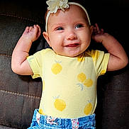 Ellie joined the competition — help win amazing prizes! baby, child, smiling, yellow_onesie, denim_shorts, headband, flower, arms_up, lying_down, lemon_print, cute, happy, infant, clothing, portrait, closeup, skin, face, eyes, indoor