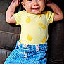 Ellie is registered to the contest to win money with this photo: baby, smiling, headband, flower, yellow_shirt, denim_skirt, lemon_pattern, couch, infant, happy, cute, child, clothing, footwear, barefeet, portrait, indoors, skin, young, toddler