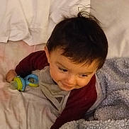 Christian is registered to the contest to win money with this photo: baby, child, infant, toddler, portrait, bed, blanket, fleece_blanket, pillow, toy, pacifier, smiling, face, eyes, hand, hair, onesie, sleeve, indoors, cozy