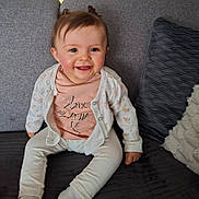 Loélye participe au concours pour gagner de l'argent avec cette photo : baby, child, smiling, sitting, couch, cardigan, shirt, text, happy, indoor, homedecor, pillow, plush, cute, person, face, hair, infant, clothing, toddler