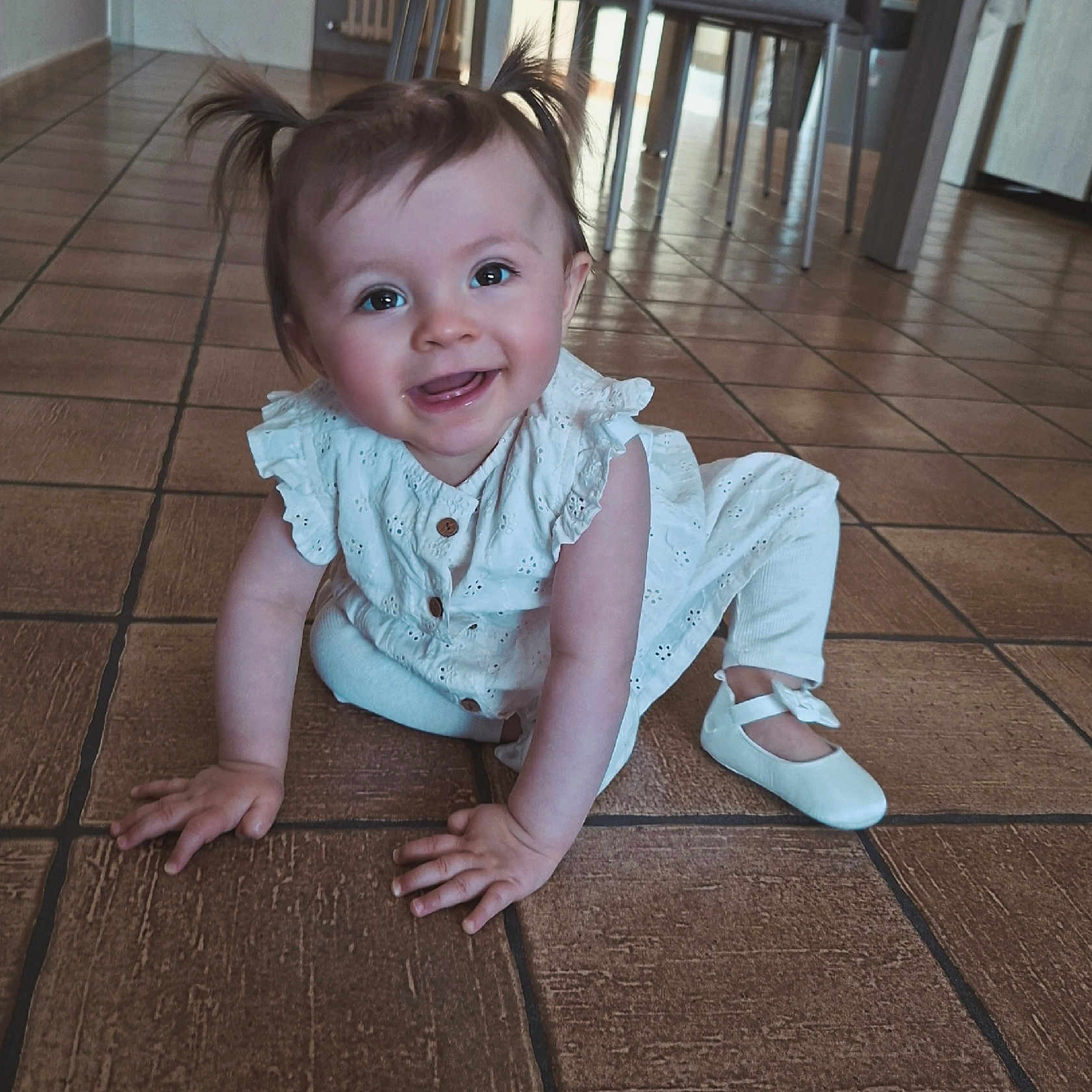 Loélye a rejoint le concours — aidez-le/la à gagner de superbes lots ! baby, girl, smiling, crawling, pigtails, white_dress, indoor, floor_tiles, shoes, child, happy, cute, portrait, person, infant, bright_eyes, hands, playful, home, toddler