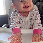 Oakley is registered to the contest to win money with this photo: baby, child, cozy, cute, face, furniture, hands, happy, high_chair, home, indoor, infant, light, pajamas, person, portrait, sitting, smiling, window, young