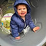 Leo joined the competition — help win amazing prizes! toddler, child, blue_jacket, hood, smile, playground, slide, tunnel, crawling, happy, outdoor, gray, plastic, person, face, hands, clothing, daylight, young_child, curious
