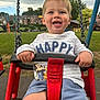Leo is registered to the contest to win money with this photo: toddler, child, swing, playground, smiling, happy, outdoor, grass, clothing, shorts, toy, park, daylight, face, person, seat, chain, mickey_mouse, sky, nature