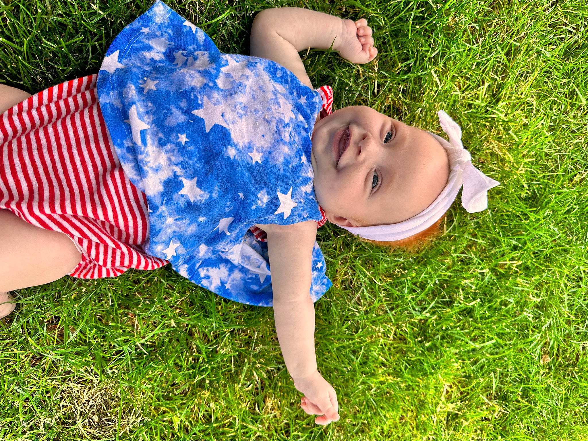 Addalyn is registered to the contest to win money with this photo: baby_toddler_clothing, electric_blue, fun, grass, grassland, happy, hat, human_leg, joy, lawn, leisure, pattern, people_in_nature, person, plant, shorts, sitting, smile, sun_hat, t_shirt