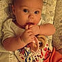 Willow joined the competition — help win amazing prizes! baby, infant, child, teething_toy, cushion, patterned_fabric, orange_pants, white_shirt, colorful_text, sitting, indoor, cute, hands, face, eyes, plush, comfort, young, adorable, portrait