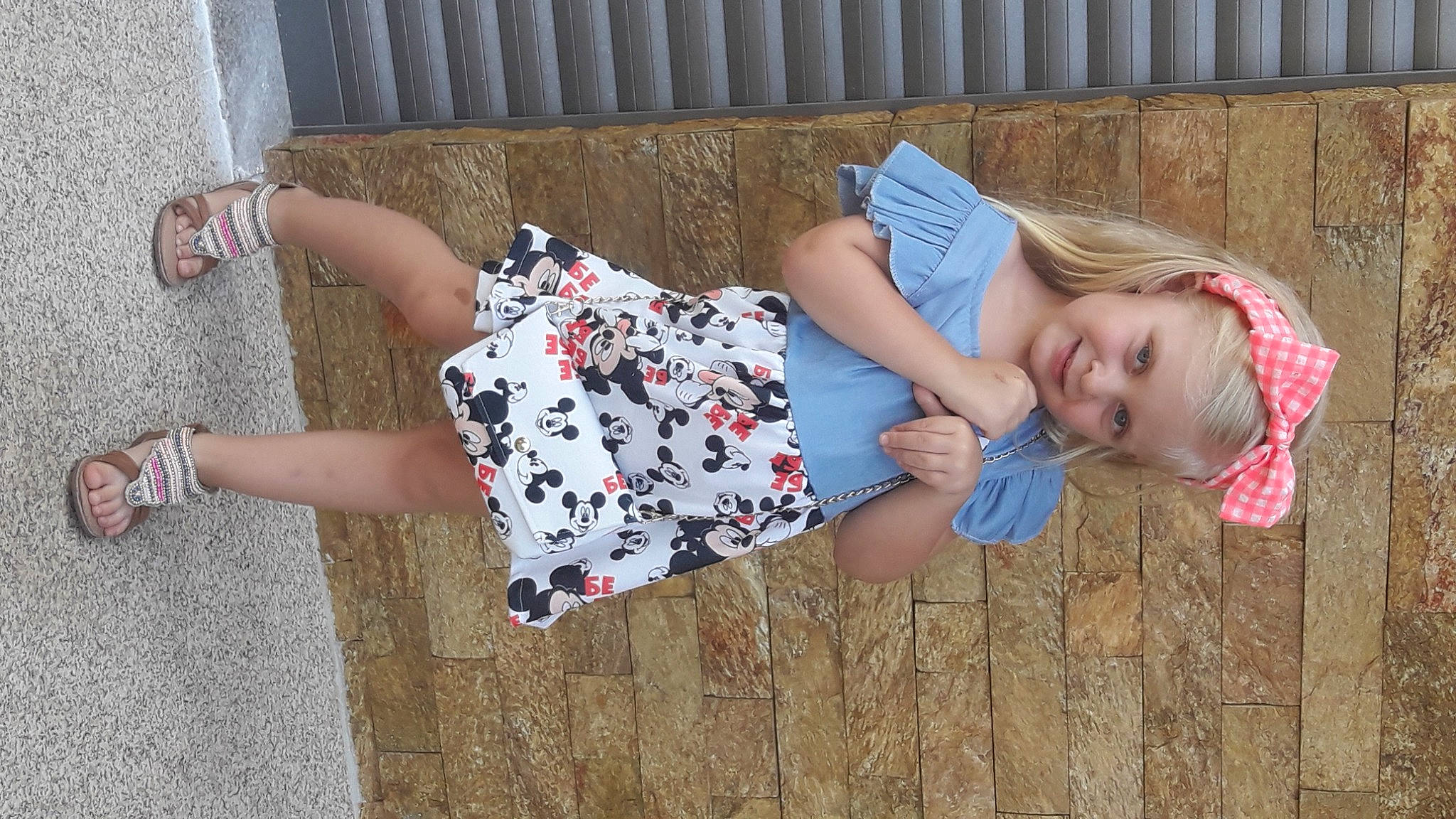 Livia participe au concours pour gagner de l'argent avec cette photo : baby_toddler_clothing, blond, calf, child, dress, grass, happy, headwear, human_leg, joy, leg, leisure, pattern, person, pink, plant, sitting, smile, textile, thigh